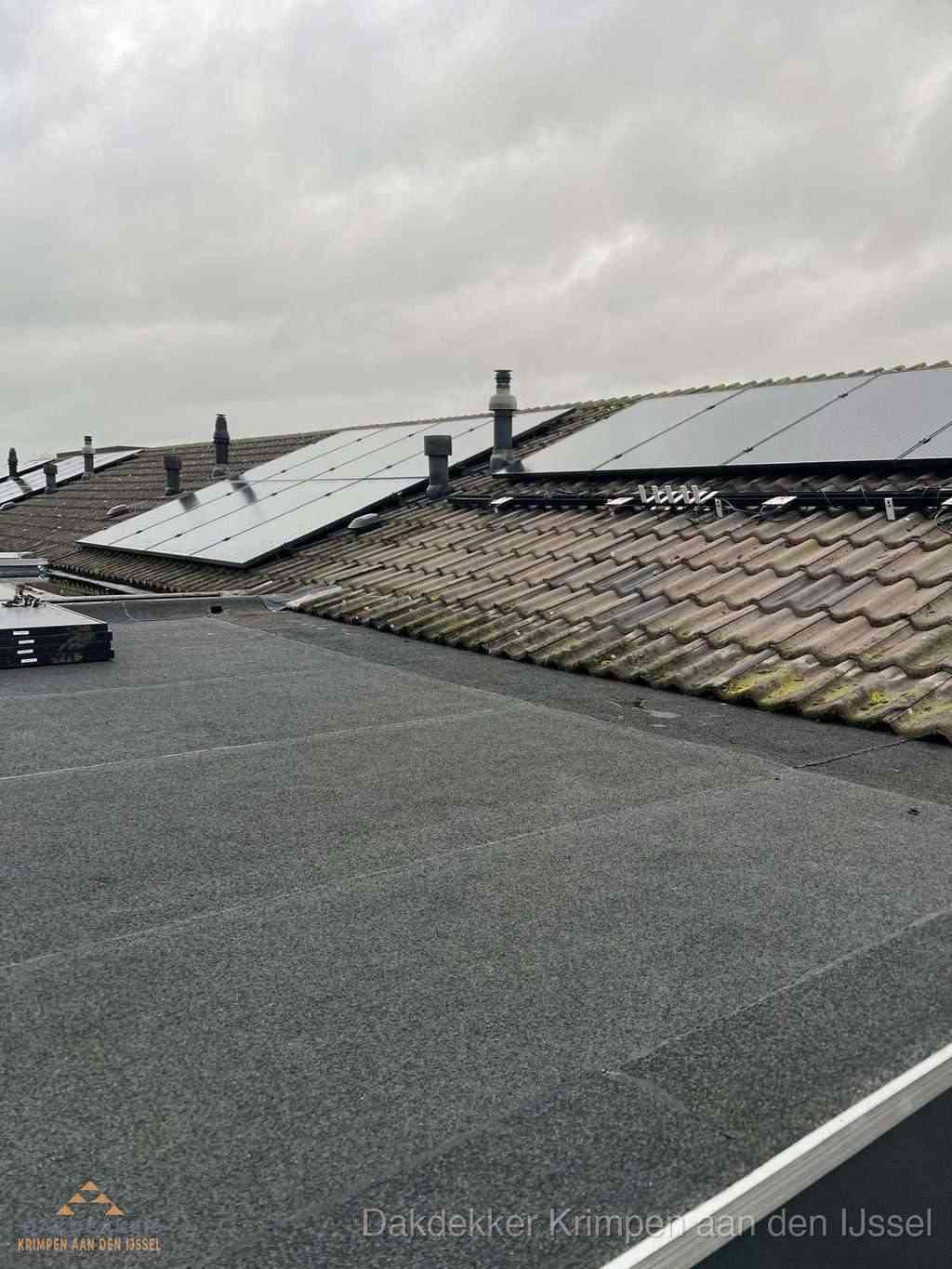 Plat dak inspectie met bitumen bedekking naast schuin pannendak in Krimpen aan den IJssel