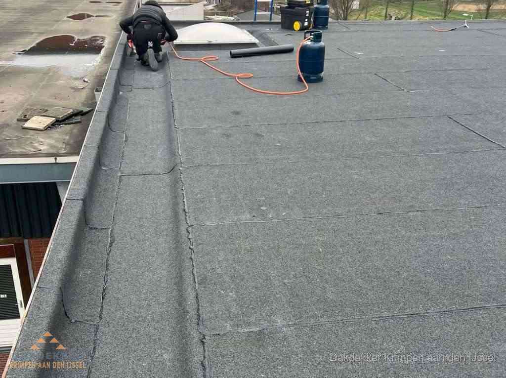 Dakdekker repareert bitumen dakbedekking op groot plat dak in Krimpen aan den IJssel