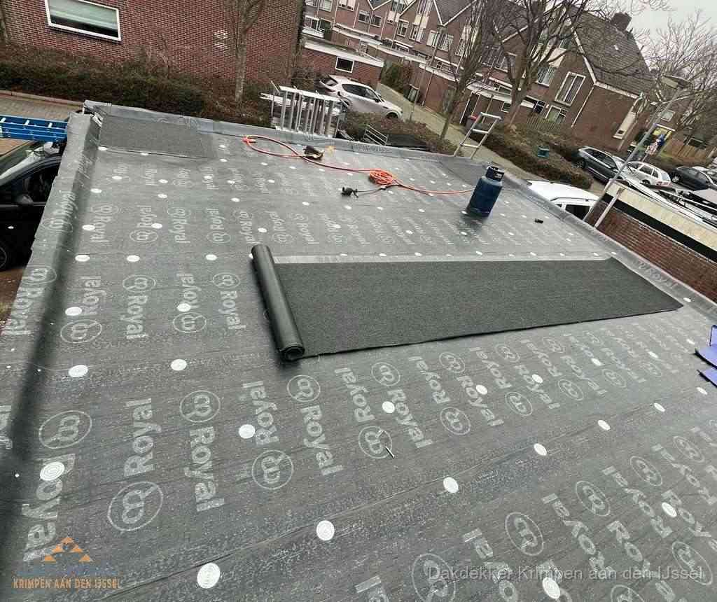 Dakdekker aan het werk met gasbrander op plat bitumen dak in Krimpen aan den IJssel